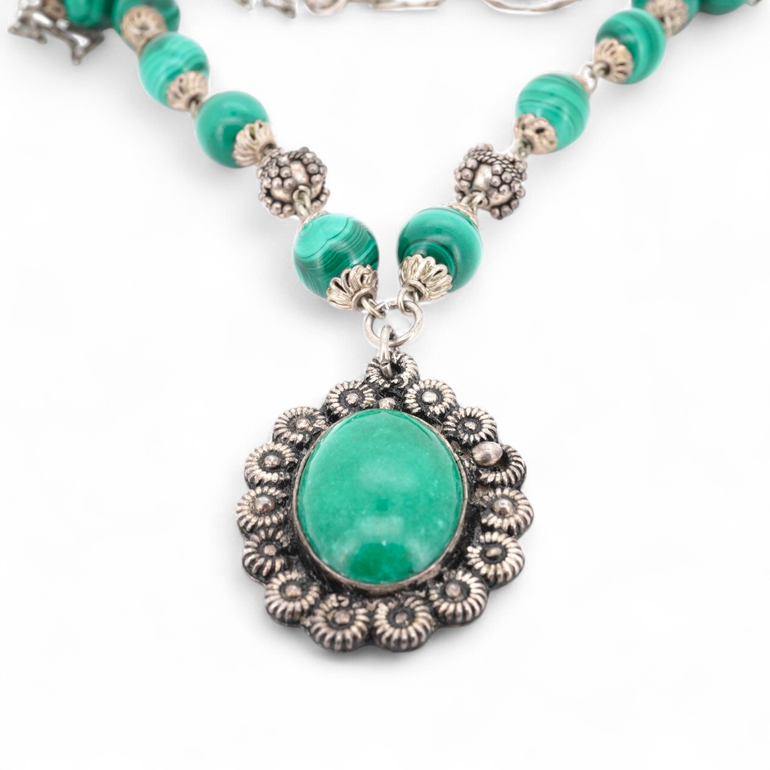 An Arts & Crafts silver and malachite necklace, early 20th century composite, the front composed of malachite beads in silver wire work mounts, suspending a green hardstone pendant in a floral silver border, necklace len